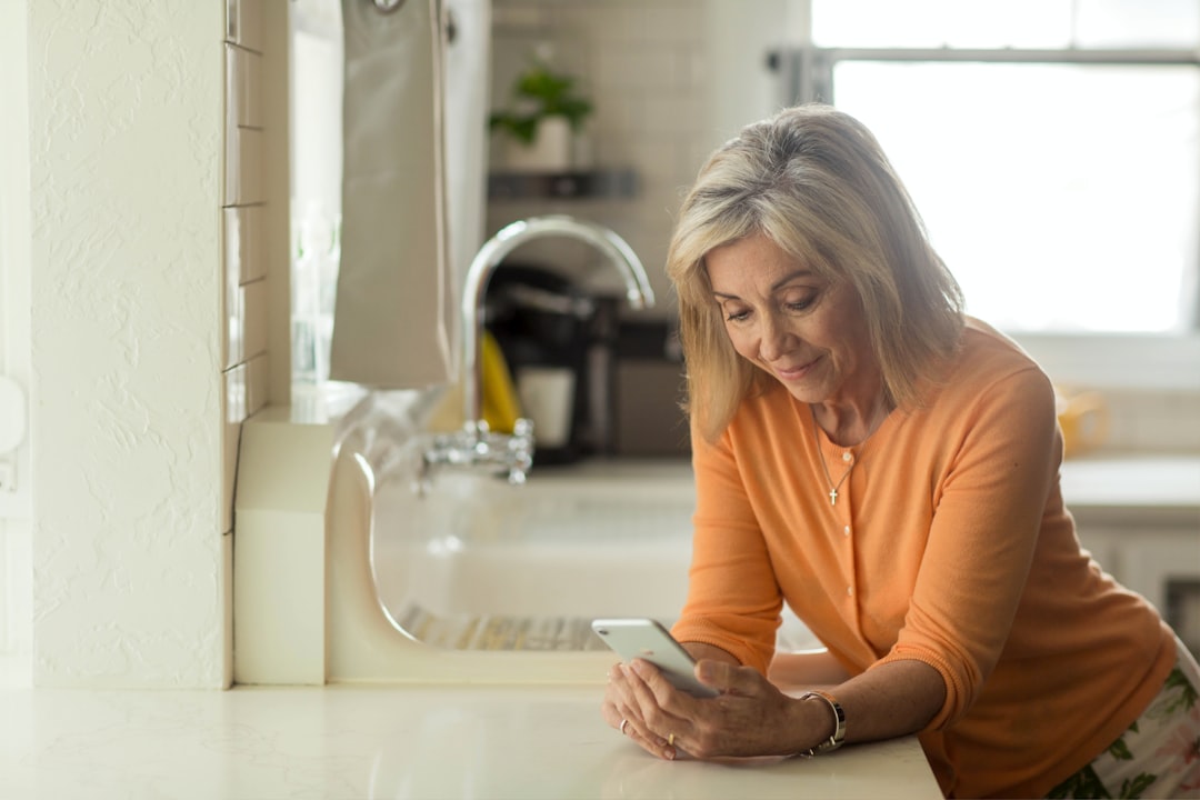 woman-in-orange-long-sleeve-shirt-using-white-smartphone-rn53lu1plzo
